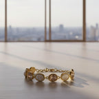 SVORA adjustable gold-tone bracelet with alternating opal and pink gemstones and a good luck charm.