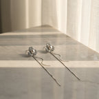 SVORA silver-tone stud earrings with three pavé-set cubic zirconia petals and a central pearl, featuring delicate chain tassels.
