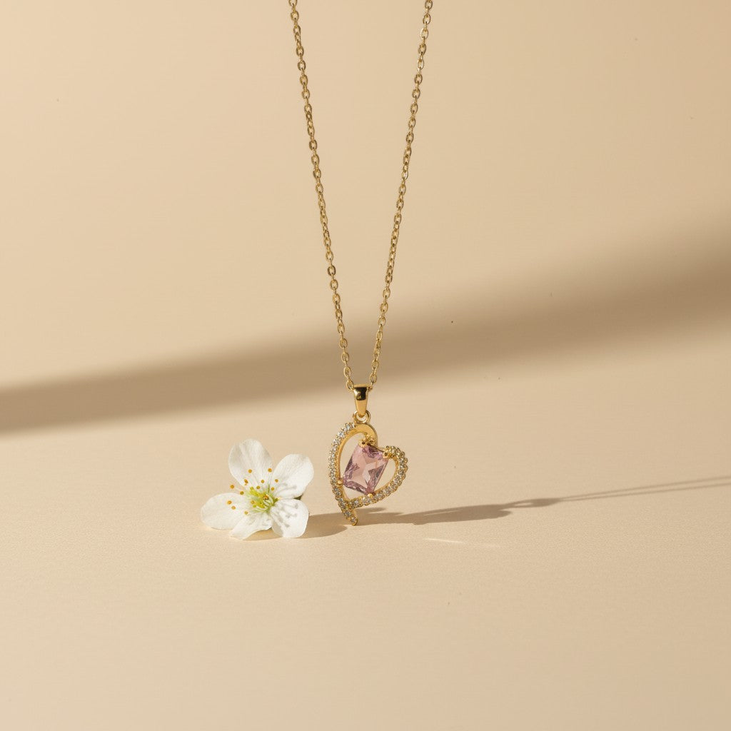 SVORA gold plated stainless steel necklace with a pink heart-shaped sapphire pendant surrounded by small clear crystals.