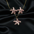 SVORA pink enamel starfish necklace and matching earrings set with gold-tone accents on a black satin background.