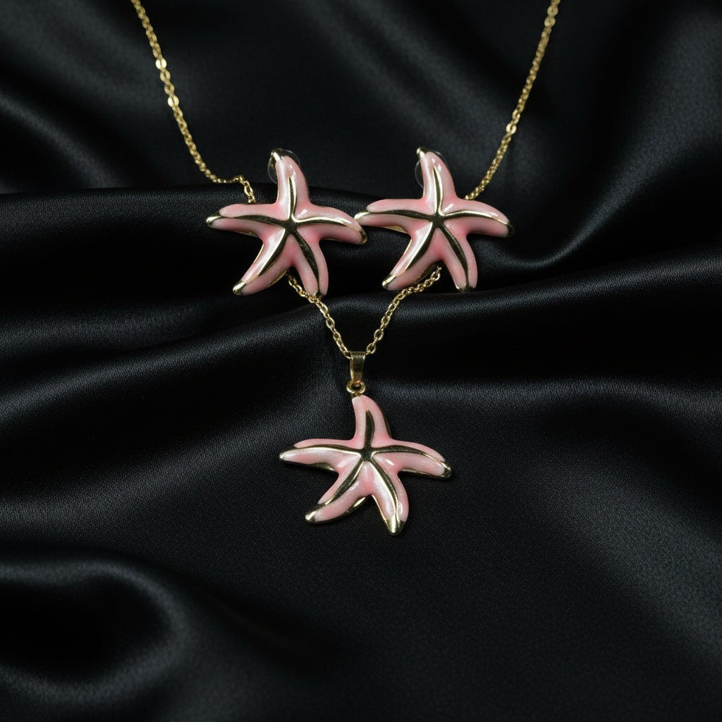 SVORA pink enamel starfish necklace and matching earrings set with gold-tone accents on a black satin background.