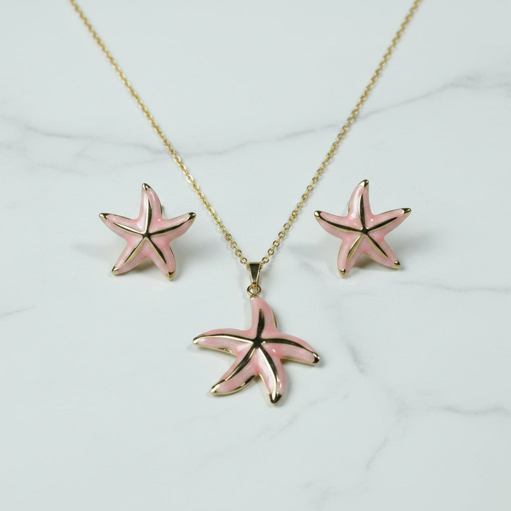 SVORA pink enamel starfish necklace and matching earrings with gold trim, set on a marble background.