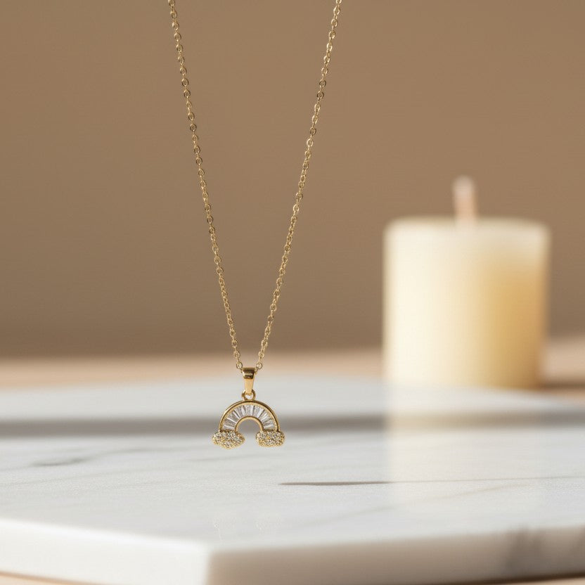 SVORA gold plated stainless steel necklace with a rainbow pendant adorned with baguette and round cubic zirconia stones, and cloud details.