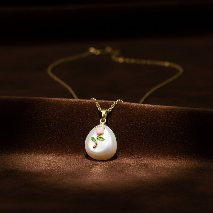 SVORA pendant necklace with a pearl drop, featuring a pink rose and green leaves design. Gold chain.