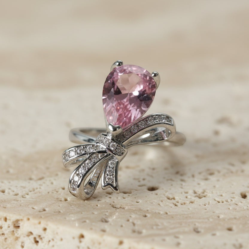 SVORA Ethereal Rose Ribbon Ring with a pear-cut pink stone and pavé clear stones on a silver band.
