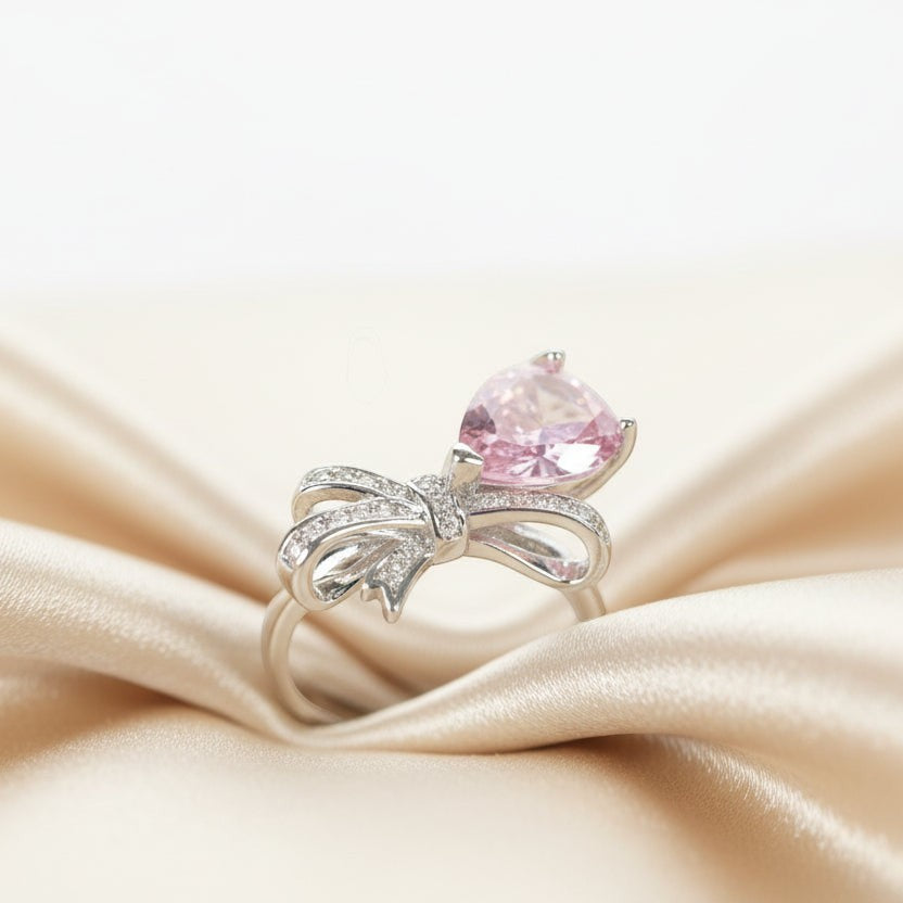 SVORA Ethereal Rose Ribbon Ring with pink pear-cut stone and pavé clear stones on a silver band.