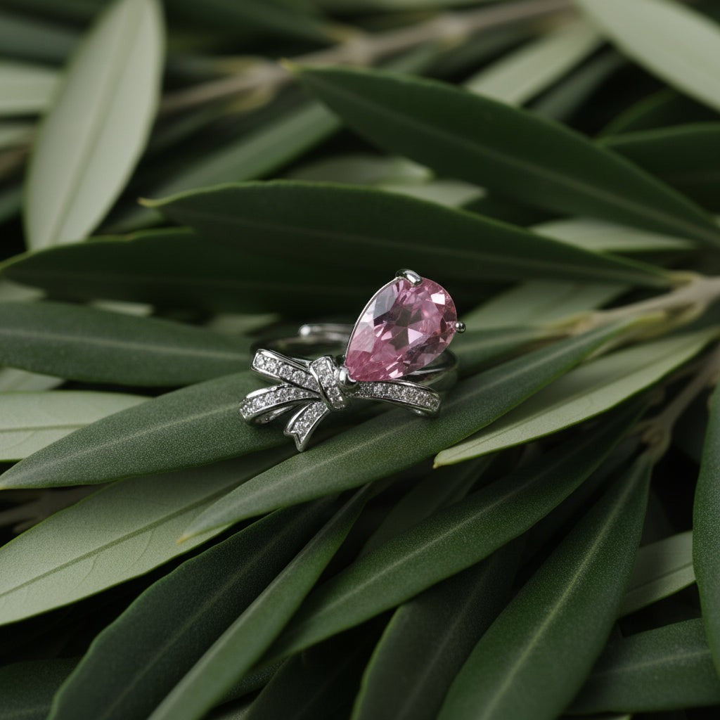 SVORA Ethereal Rose Ribbon Ring with pink pear-cut stone and pavé clear stones on a silver band.