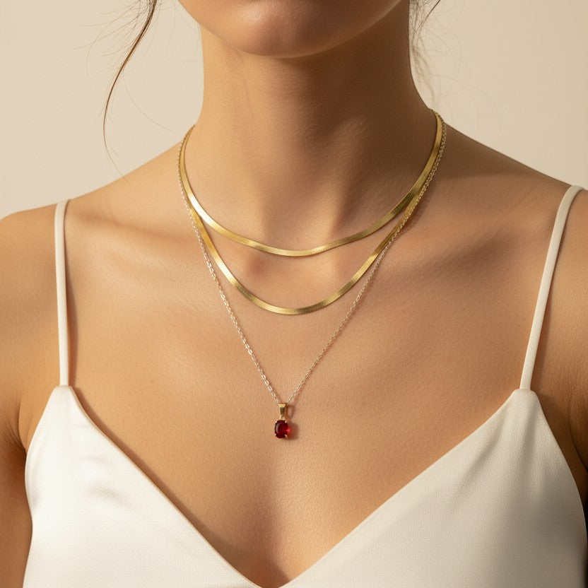 SVORA layered necklace with two gold snake chains and a ruby red crystal pendant. Gold plated stainless steel.