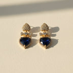 SVORA gold tone drop earrings with sapphire blue crystal hearts and pavé bow connectors.
