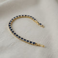 SVORA adjustable tennis bracelet with alternating sapphire blue and clear square-cut stones, set in gold-tone stainless steel.