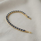 SVORA adjustable tennis bracelet with alternating sapphire blue and clear square-cut stones, set in gold-tone stainless steel.