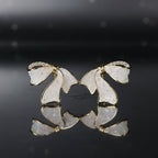 SVORA sculptural gold ribbon stud earrings with white stone inlay and pavé cubic zirconia accents.