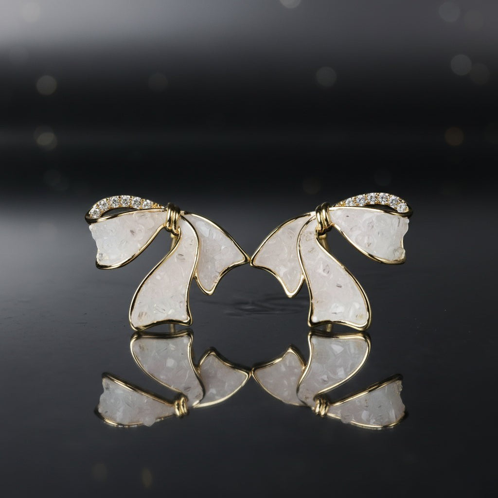 SVORA sculptural gold ribbon stud earrings with white stone inlay and pavé cubic zirconia accents.