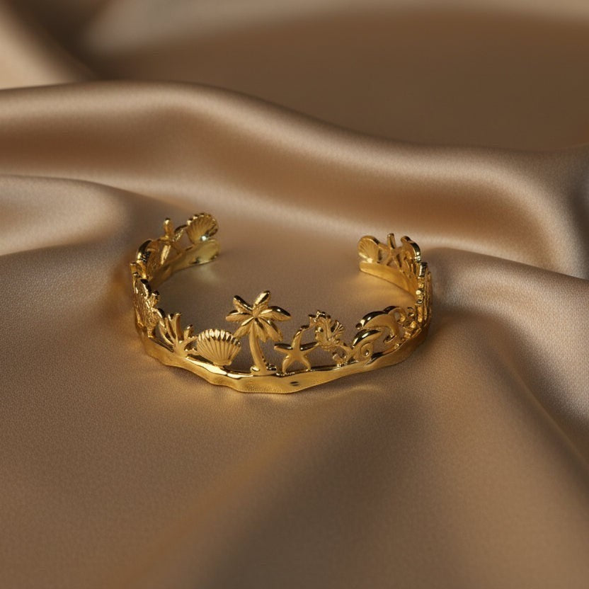 SVORA gold plated stainless steel Seascape cuff bracelet with palm trees, shells, and dolphins. Adjustable.