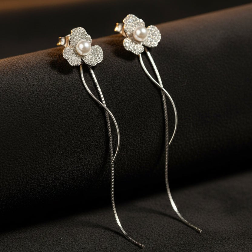 SVORA silver-tone stud earrings with three-petal flower design, pavé-set with cubic zirconia and a central pearl.