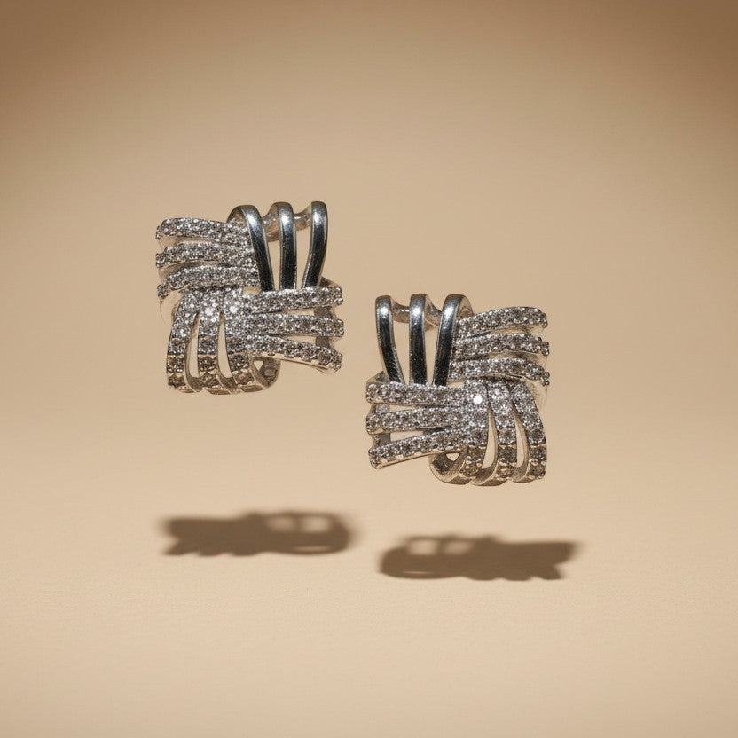 SVORA silver rhodium-plated stainless steel stud earrings with interlocking square design and cubic zirconia stones.
