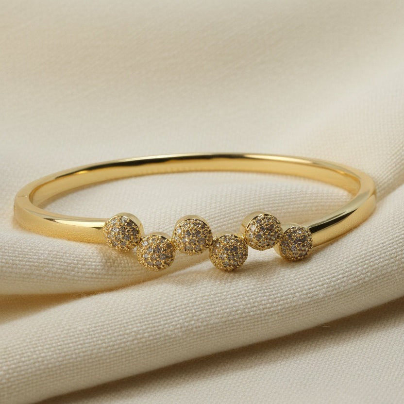 SVORA gold plated stainless steel bangle bracelet with six pavé cubic zirconia domes in a row. Modern, waterproof jewelry.