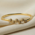 SVORA gold plated stainless steel bangle bracelet with six pavé cubic zirconia domes in a row. Modern, waterproof jewelry.