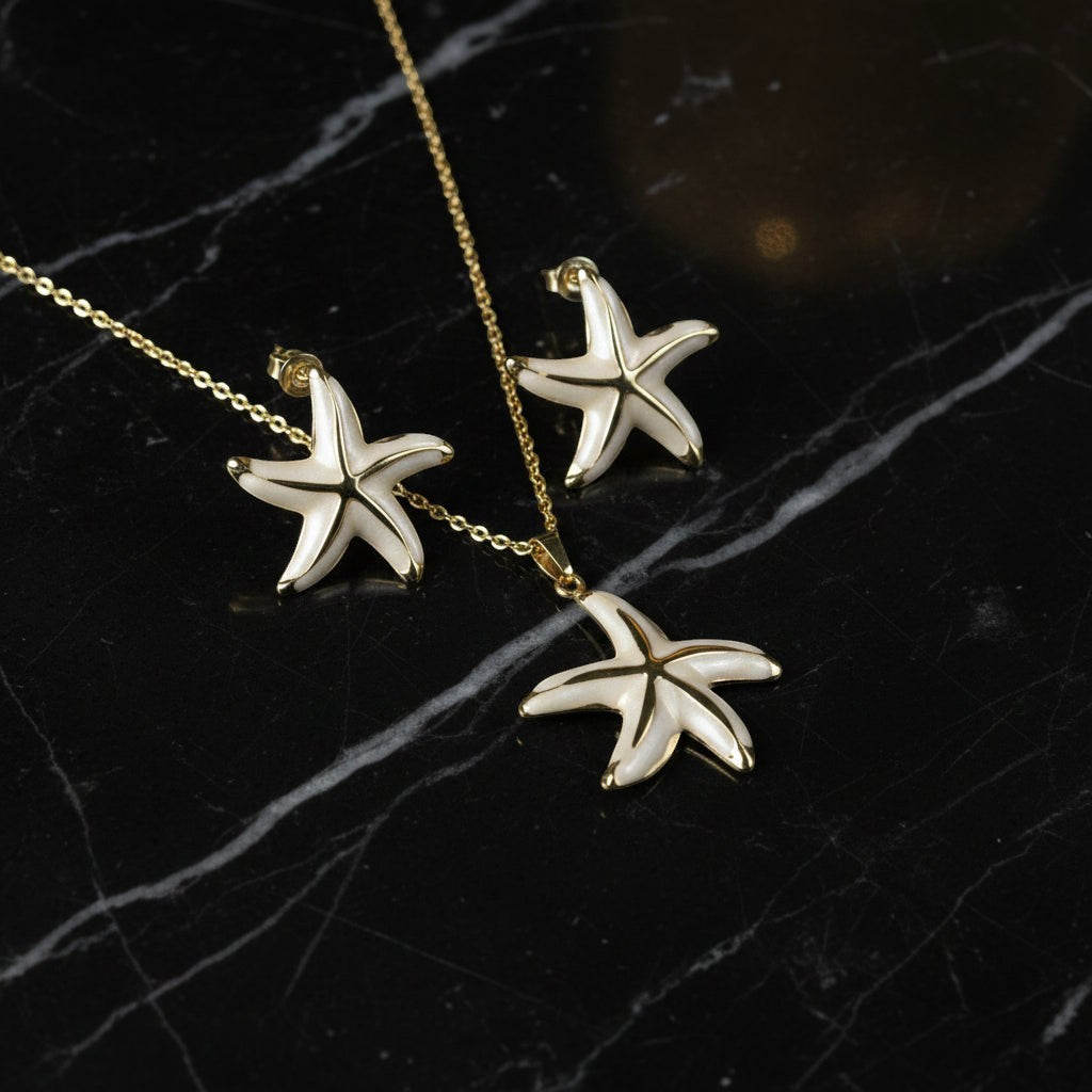 SVORA white enamel starfish necklace and earrings set with gold edges on a black marble background.