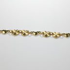 SVORA gold curb chain bracelet with seven heart charms, four textured and three solid. Adjustable with lobster clasp.