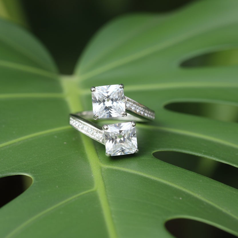 SVORA Toi et Moi ring with two princess-cut clear stones on rhodium-plated band with channel-set baguettes. Stainless steel.