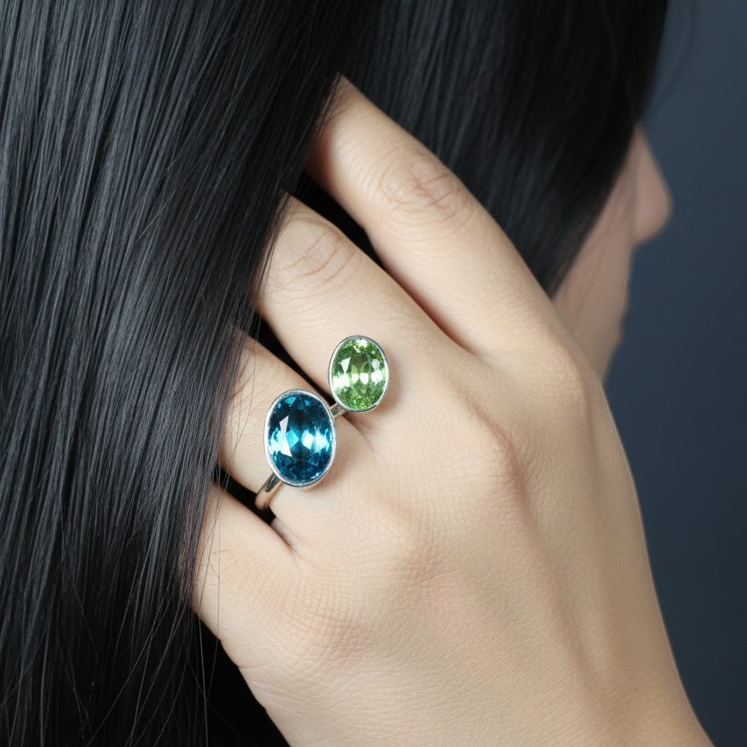 SVORA Toi et Moi ring with oval sapphire blue and emerald green stones on a silver band. Adjustable.