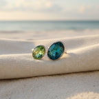 SVORA Toi et Moi ring with oval sapphire and emerald stones on a beach setting.