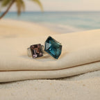 SVORA Toi et Moi Twilight Sapphire Ring with abstract blue and emerald-cut pinkish-purple stones on a ribbed silver band.