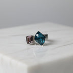 SVORA Toi et Moi Twilight Sapphire Ring with blue abstract-cut and pinkish-purple emerald-cut stones on ribbed stainless steel band.