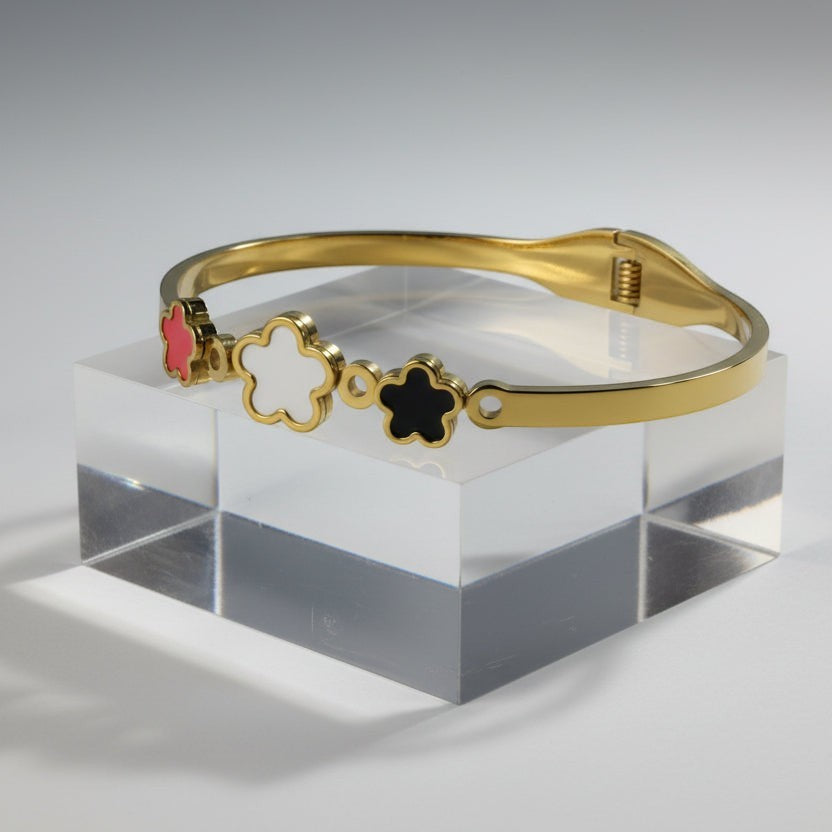 SVORA gold plated stainless steel bracelet with three five-petal flower charms in black, white, and red.