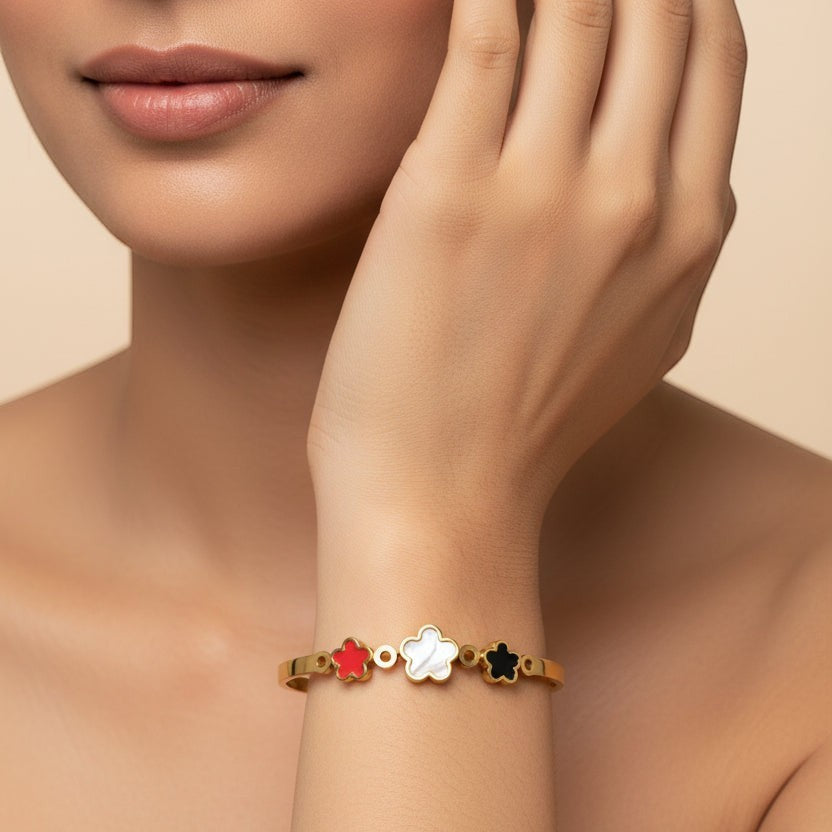 SVORA gold plated stainless steel bracelet with three flower charms in red, white, and black.