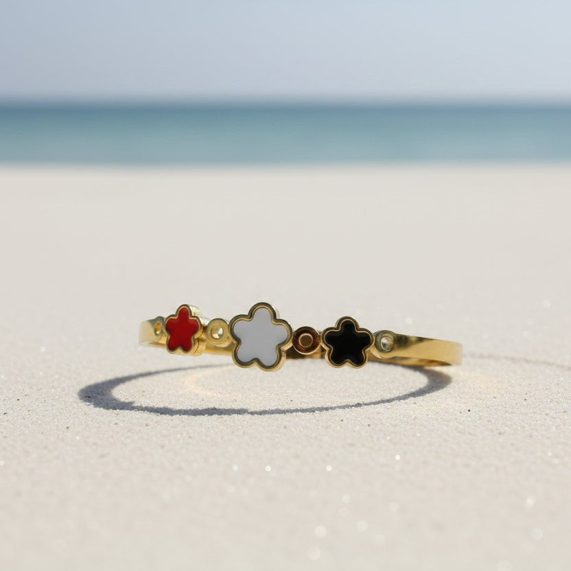 SVORA gold plated stainless steel bracelet with three five-petal flower charms in red, white, and black.