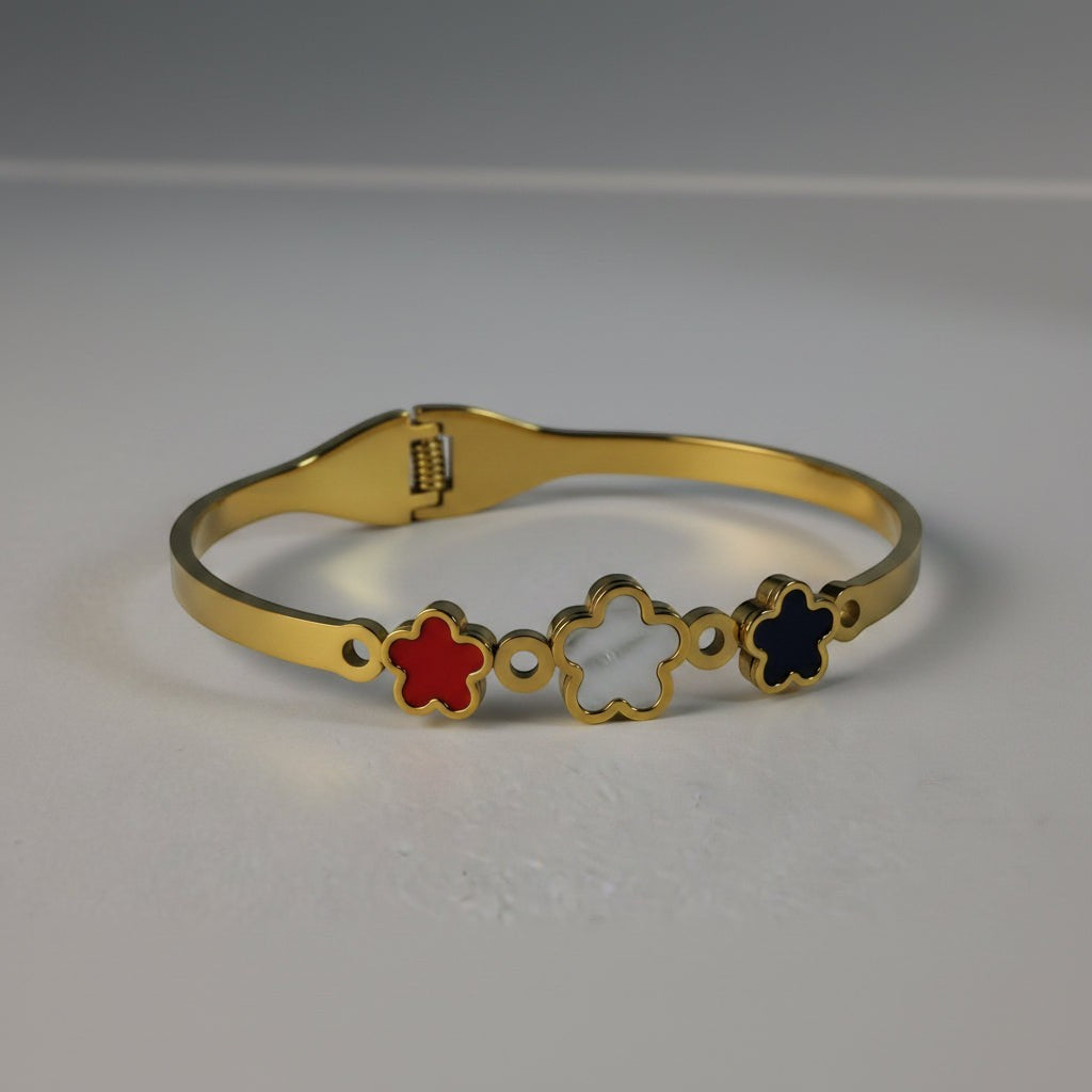 SVORA gold plated stainless steel bracelet with three five-petal flower charms in red, white, and black.