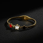 SVORA gold plated stainless steel bracelet with three five-petal blooms in red, white, and black.