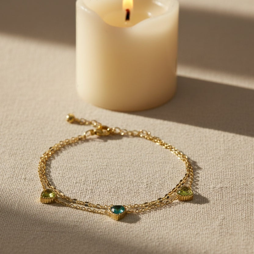 SVORA Triple Emerald Layered Chain Bracelet with gold-plated stainless steel and green cubic zirconia stones.