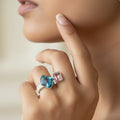 SVORA Toi et Moi Twilight Sapphire Ring with blue abstract-cut and pink emerald-cut stones on ribbed stainless steel band.