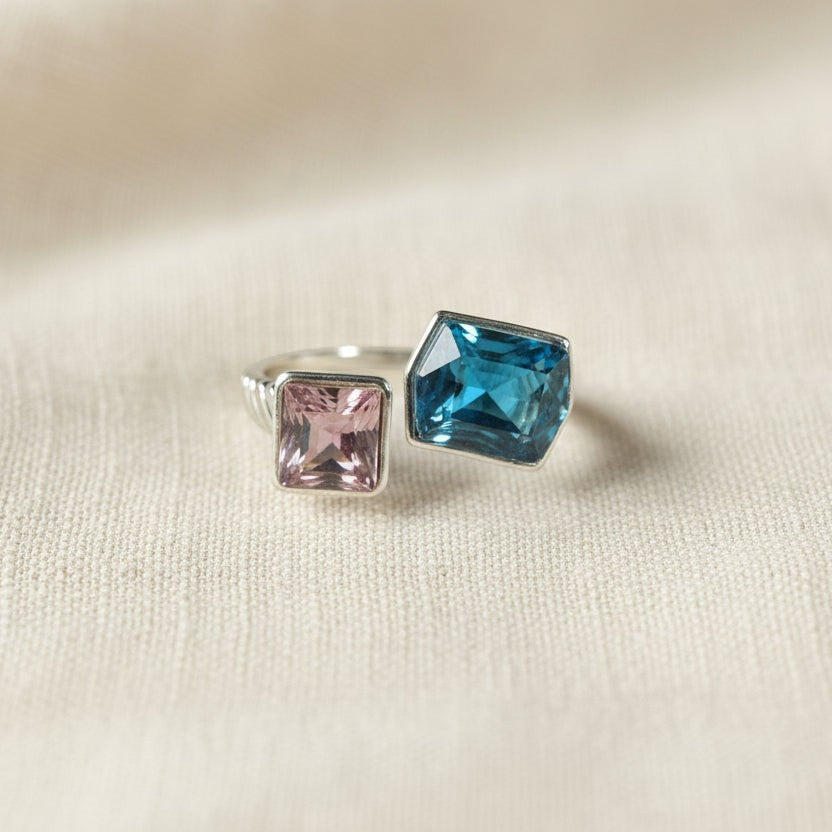SVORA Toi et Moi Twilight Sapphire Ring with blue abstract-cut and pink emerald-cut stones on ribbed stainless steel band.