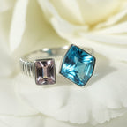 SVORA Toi et Moi Twilight Sapphire Ring with blue abstract-cut and pink emerald-cut stones on ribbed silver band.