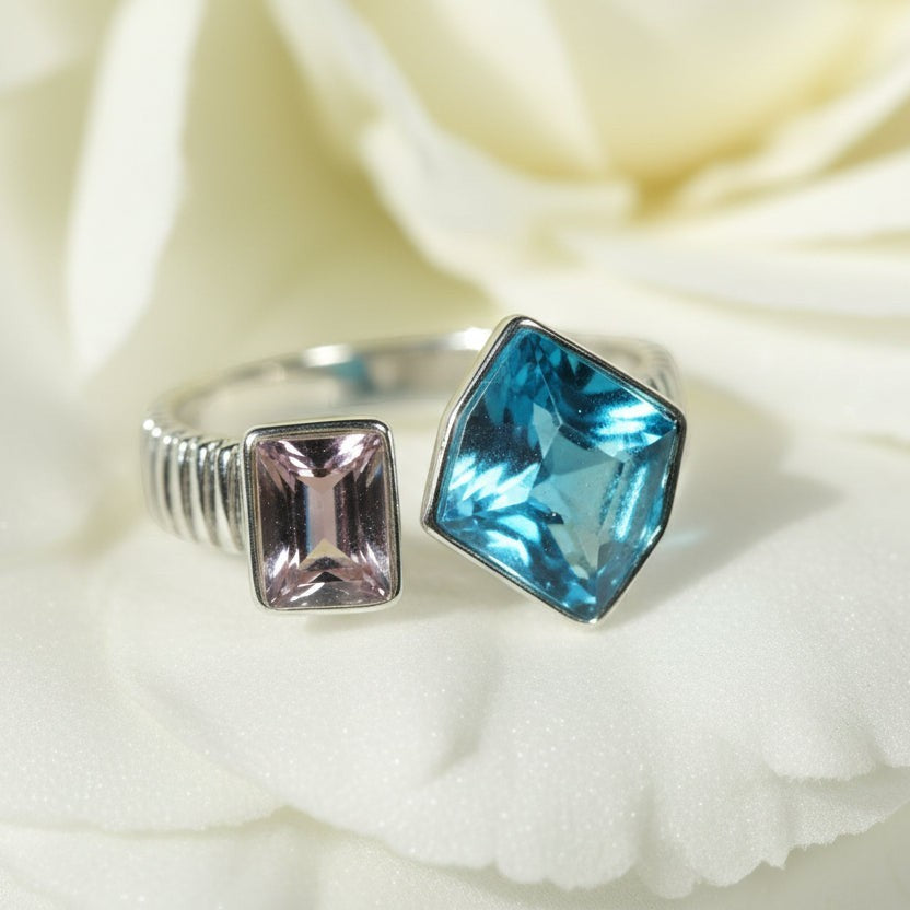 SVORA Toi et Moi Twilight Sapphire Ring with blue abstract-cut and pink emerald-cut stones on ribbed silver band.