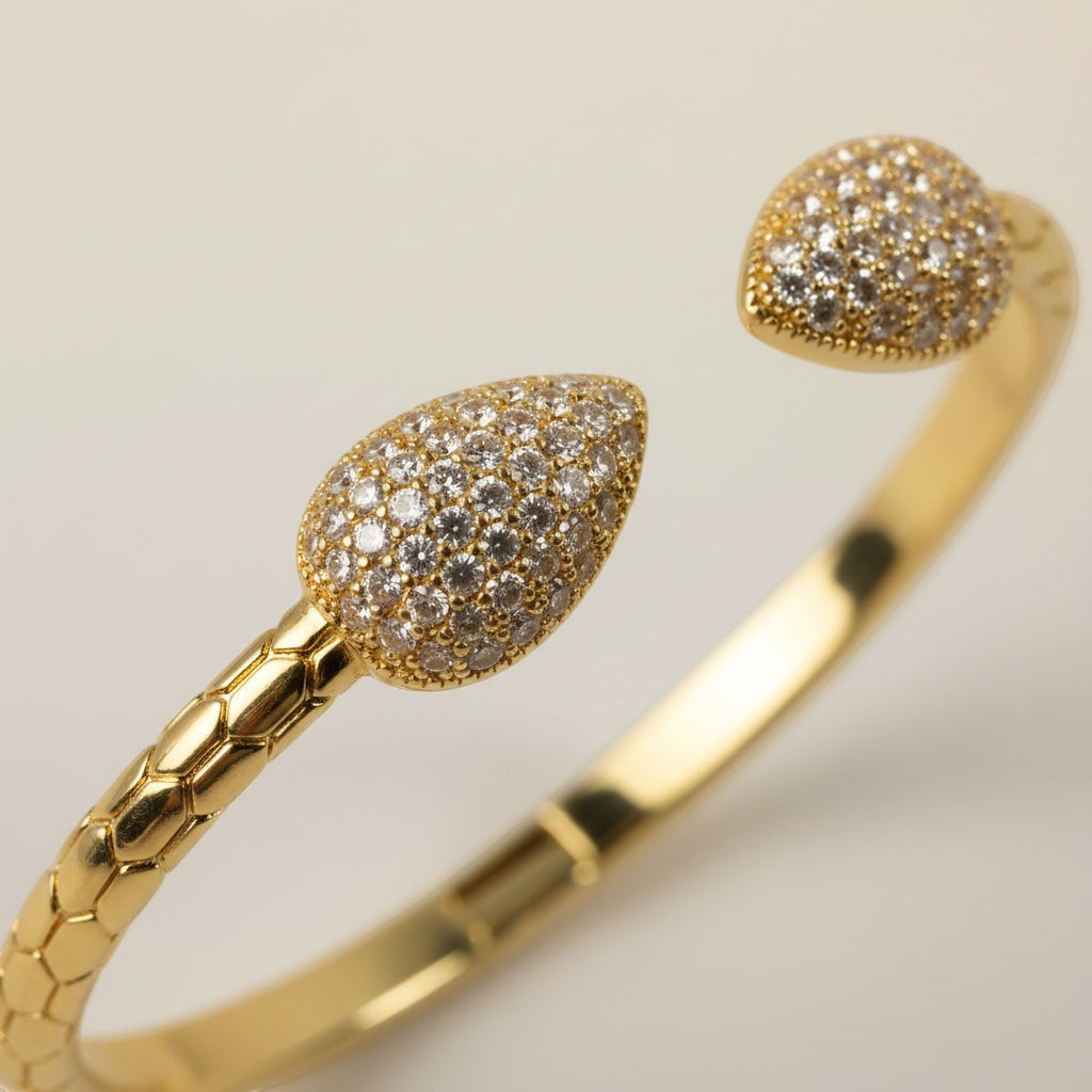 SVORA gold plated stainless steel cuff bracelet with pave leaf ends and scaled band. Cubic zirconia stones.