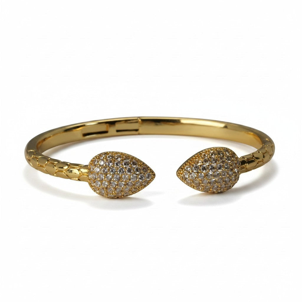 SVORA gold plated stainless steel cuff bracelet with pave cubic zirconia leaf ends and scaled band.