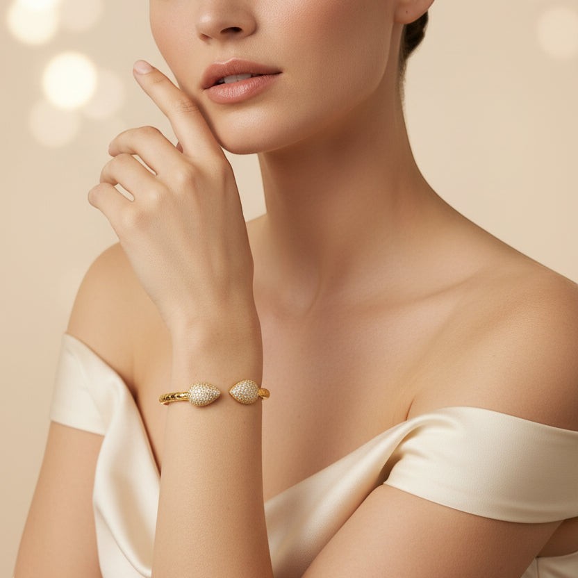 SVORA gold plated cuff bracelet with pavé leaf ends and scaled band detail, adorned with cubic zirconia.