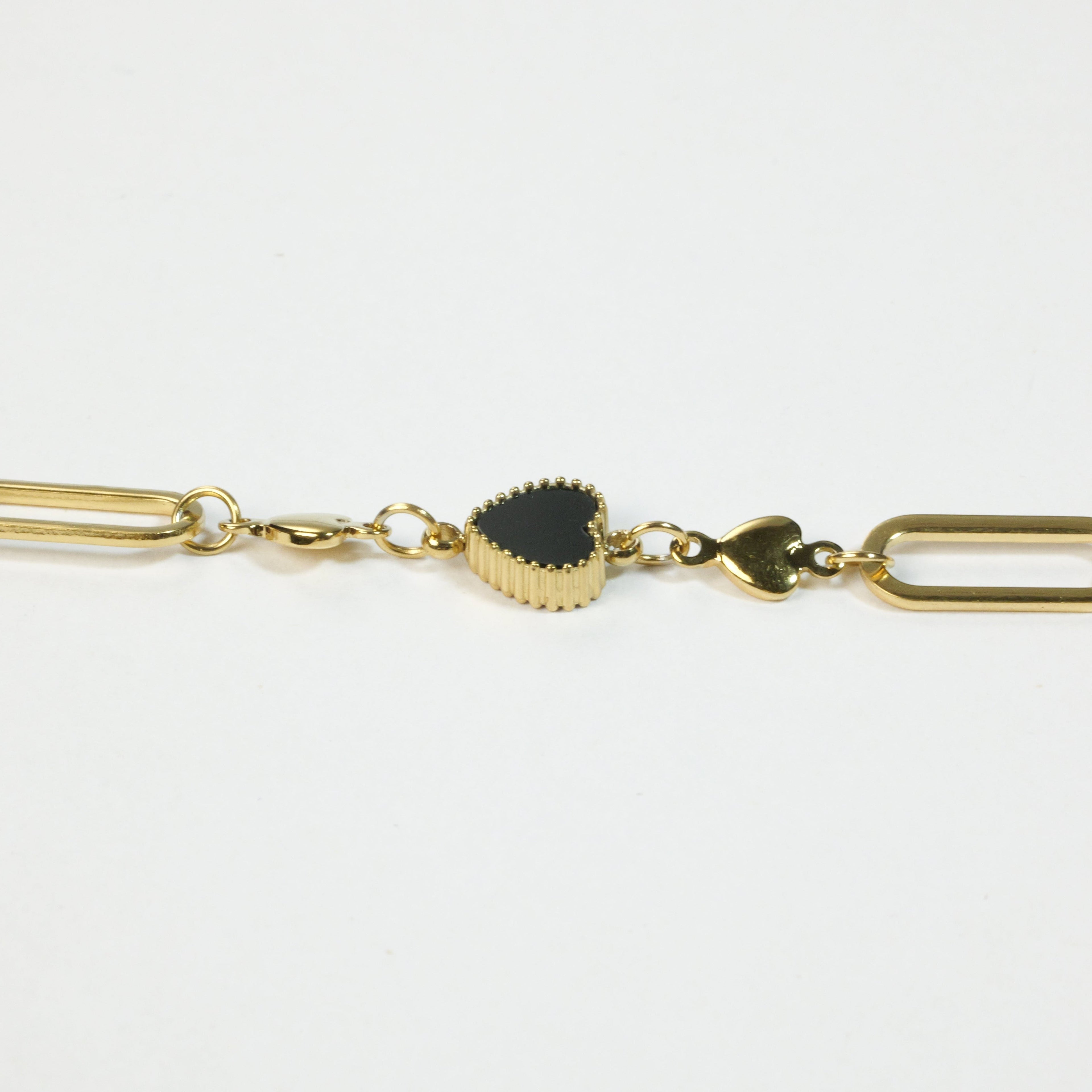 SVORA gold twisted rope chain bracelet with a black heart charm and two smaller gold heart charms.