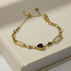 SVORA gold twisted rope chain bracelet with a black heart charm and smaller gold heart charms.