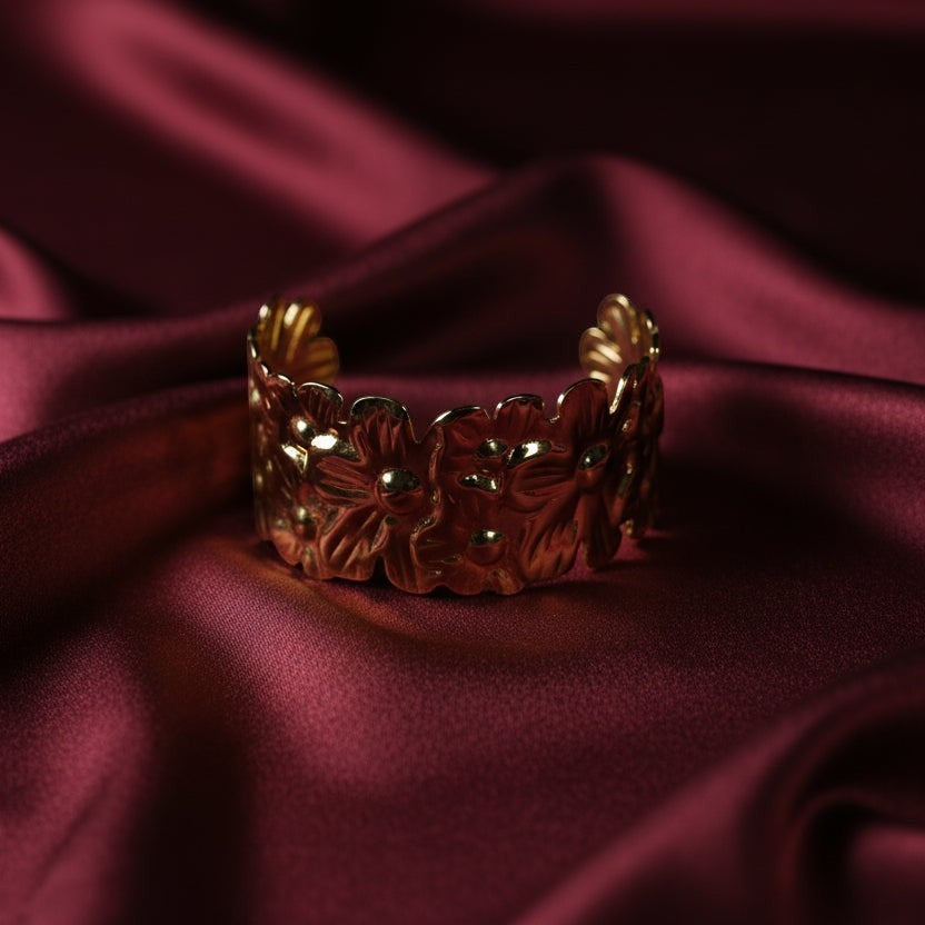 SVORA gold plated stainless steel cuff bracelet with a detailed floral design. Adjustable and hypoallergenic.