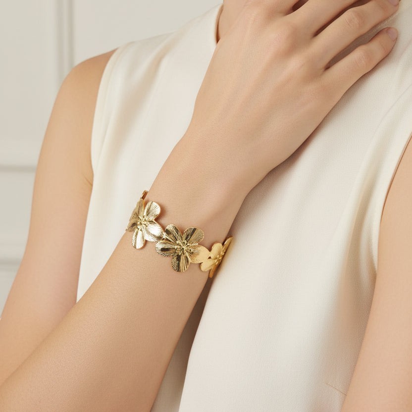 SVORA gold cuff bracelet with five sculpted floral blooms, diamond-cut finish, 18K gold plated stainless steel.