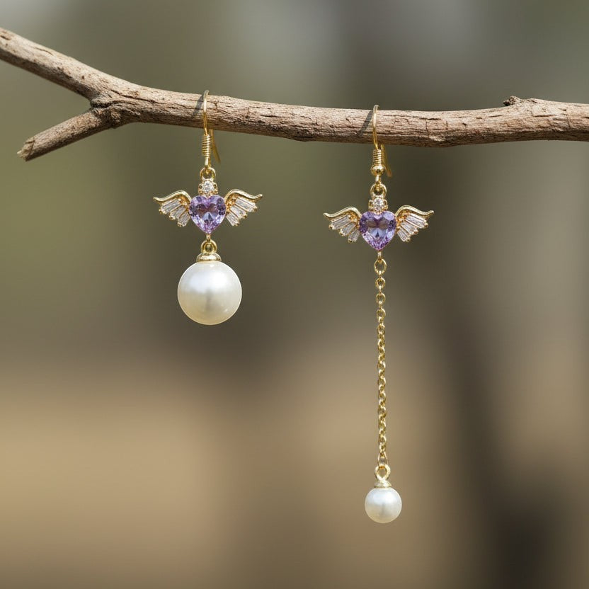 SVORA asymmetric gold-tone earrings with purple heart charms, wings, and pearl drops.