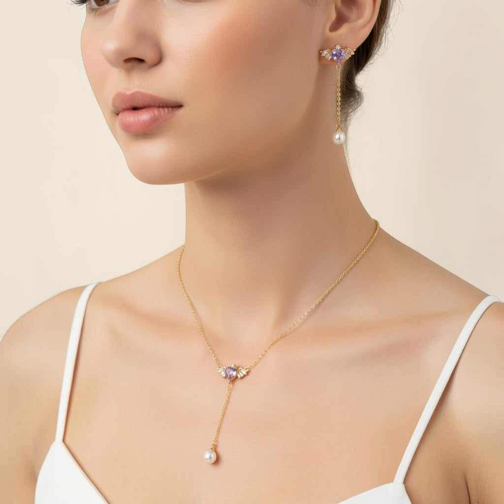 SVORA gold-tone asymmetric necklace and earrings set with winged purple heart charms and pearl drops.