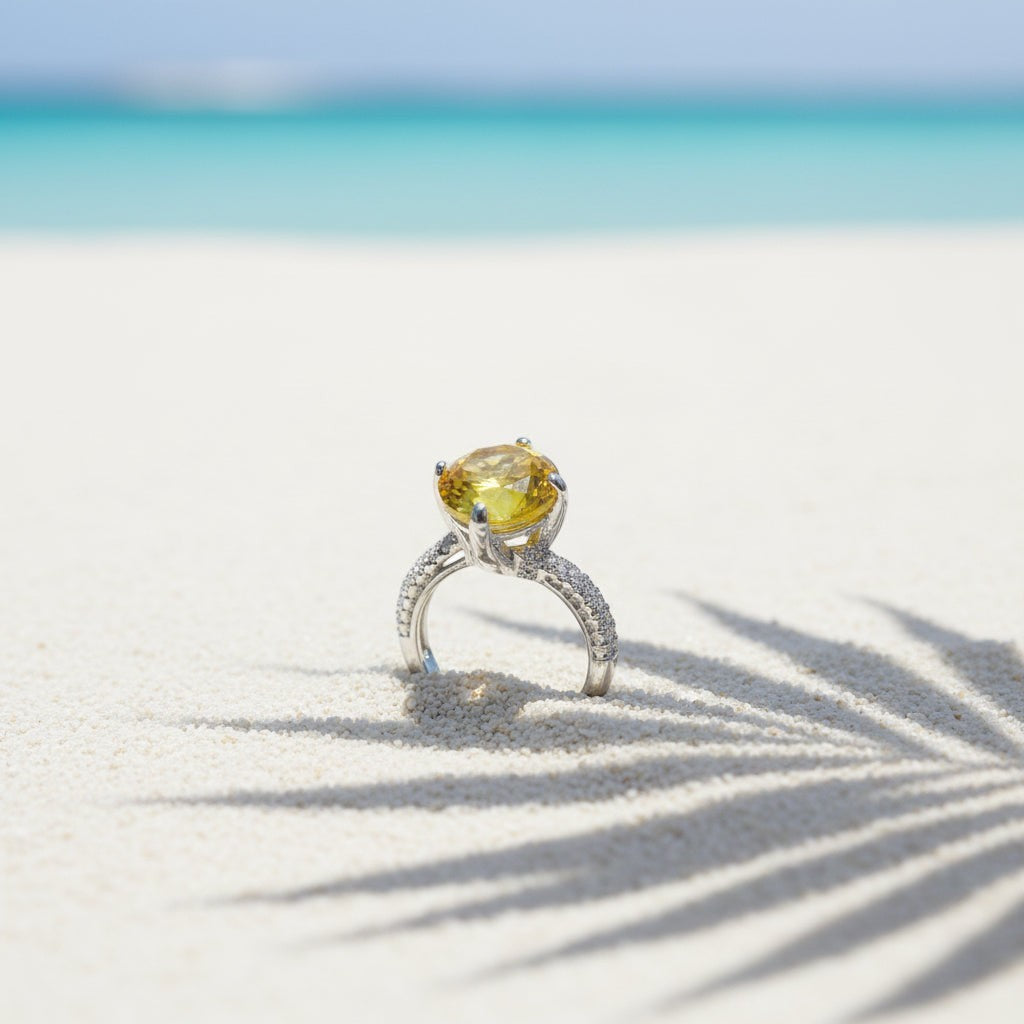 SVORA Ethereal Yellow Sapphire Solitaire Ring with pavé shoulders on a white sand beach.
