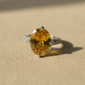 SVORA Ethereal Yellow Sapphire Solitaire Ring with oval-cut yellow stone, pavé shoulders, and rhodium-plated stainless steel band.